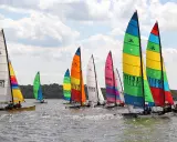 Course de Hobie Cat 18, voiles multicolores et blanches, sur l'eau par temps nuageux. Fiche technique du Hobie Cat 18.
