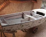 Un dériveur Caravelle polyester en cours de restauration, sur sa remorque. La coque est décapée, prête pour une nouvelle peinture.