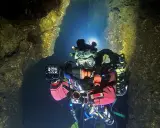 Plongée dans une grotte sous-marine, Xavier Meniscus filme les parois rocheuses éclairées par ses lampes.