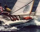 Deux personnes naviguent sur un dériveur Wizz, le bateau fend les vagues dans une joyeuse course.
