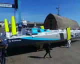 Équipe poussant un **60 pieds IMOCA** de course au large, le Safran, dans un chantier naval.