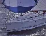 Voilier blanc naviguant sur des eaux agitées, ses voiles bleues et blanches gonflées par le vent. Le nom "DIE-TERRY" est visible sur la coque.
