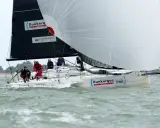 Un voilier "Dunkerque Voile" navigue avec un équipage concentré. Eliott Coville, peut-être à bord, profite de la course.
