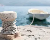 Un cordage est enroulé autour d'une borne en pierre sur un quai, prêt pour le prochain pendille bateau.