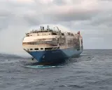Le cargo Felicity Ace, en feu, dérive sur une mer agitée. De la fumée s'échappe de ses ponts supérieurs.
