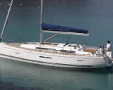 Un voilier blanc Dufour 405 Grand Large navigue sur une eau turquoise. Un homme est au poste de barre.