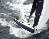 Un voilier de course fend les vagues, ses voiles noires et blanches gonflées par le vent. On dirait qu'il nous montre comment naissent les bateaux, prêts à conquérir l'océan.