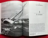 Un voilier navigue dans une mer agitée, ses voiles gonflées par le vent. Alain Gliksman, passionné de voile, admire cette scène.