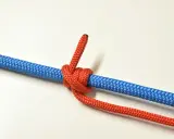 Un nœud de bosse rouge est solidement attaché à une corde bleue, prêt pour une aventure.