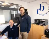 Dimitri Caudrelier et son collègue dans leur bureau, avec le logo "Reborn for Tomorrow" au mur.
