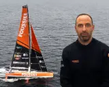 Sébastien Marsset, skipper du voilier Foussier, prêt pour la course. Le bateau orange et noir fend les vagues.