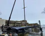 Le trimaran Gitana 18, prêt pour l'aventure, est soulevé par une grue à Lorient. Une foule nombreuse est rassemblée pour admirer ce géant des mers.
