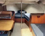 L'intérieur du Jeanneau Brio offre un espace de vie confortable avec des banquettes en tissu noir, une table en bois et des boiseries chaleureuses.