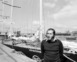 Un homme pose devant le voilier "Club Mediterranee". Ce navigateur célèbre semble prêt pour une nouvelle aventure maritime.