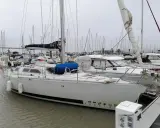 Un voilier blanc, "PEELIN", est amarré dans un chantier naval. D'autres bateaux sont visibles en arrière-plan.