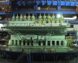 Un immense moteur vert, prêt à propulser un porte-conteneurs, se dresse dans un atelier de construction navale.