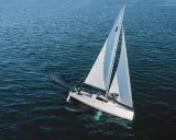 Un voilier blanc navigue sur une mer bleue. Sa quille est visible sous l'eau, stabilisant le bateau.