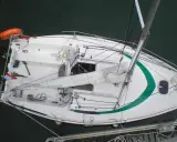 Voilier blanc avec une bande verte, prêt pour une sortie tonique. 23 avis positifs sur sa performance.