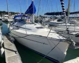 Bavaria 32, un voilier blanc avec une voile bleue, amarré dans un port. Avis sur ce modèle de bateau.