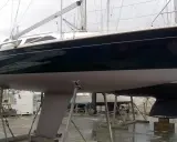 Un voilier aux lignes élégantes, posé sur des supports, attend son heure. Son allure évoque un voilier suspens, prêt à fendre les flots.