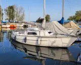 Un voilier blanc, prêt pour l'aventure, est amarré dans un port paisible. Le reflet du voilier sauvignon sur l'eau calme est saisissant.