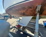 Vue du dessous d'un voilier sur bers. Le safran est visible, prêt pour l'étape 22 de la fiche technique.