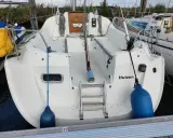 Vue arrière d'un voilier blanc amarré, avec le nom "Huizen" écrit sur la coque. Une échelle de bain est visible, ainsi que des pare-battages bleus. Le premier des 265 avis est prêt à être lu.