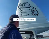 Un homme regarde une voile géante ornée du logo Michelin. Le Télégramme est affiché sur la voile.