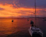 Coucher de soleil sur la mer avec des voiliers. Le tarif destruction bateau est une préoccupation pour certains, mais ici, la beauté règne.