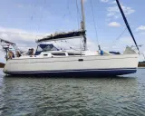 Un voilier Sun Odyssey 35, blanc avec une bande bleue, navigue paisiblement sur une mer calme. Les avis sur ce bateau sont positifs.