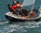 Le voilier "Toffee" navigue sur une mer agitée, quatre personnes à bord profitent de la balade.