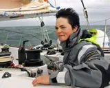 La navigatrice Ellen MacArthur, compagnon de bord sur un voilier, ajuste une voile.
