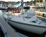 Deux personnes sur un voilier blanc, un Kelt 620, dans un port. Les avis sur ce bateau sont positifs.