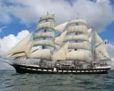 Le Belem, majestueux trois-mâts, navigue fièrement sous un ciel bleu et nuageux, rappelant les grandes traversées vers Bayonne.