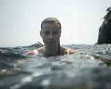 Marion Moriceau, le visage émergeant des vagues, le regard intense, baignée par la lumière du jour.