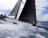 Équipage sur un voilier blanc, gery trentesaux, naviguant sur une mer agitée sous un ciel nuageux.