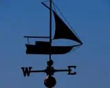 Girouette en forme de voilier, indiquant le vent. Un outil de météo IA pour naviguer.