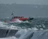 Bateau de sauvetage SNS 068 naviguant dans une mer agitée, affrontant la tempête. Les vagues déferlent sur la proue.