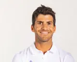 Portrait souriant de Kévin Peponnet, athlète français en polo blanc, sur fond clair.