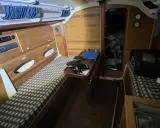 Intérieur d'un voilier Trident 80. Banquette, table pliante, rangement et couchette.