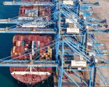 Grands portiques bleus en action, chargeant des conteneurs sur un navire. La capacité porte conteneur est impressionnante, montrant la logistique mondiale.