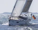 Le voilier Sirius 40 DS "Gryps" navigue sur une mer scintillante, pavillon allemand au vent.