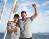 Guillaume Pirouelle et son coéquipier célèbrent une victoire sur l'eau, bras levés et souriants, sous un ciel bleu.