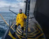 Clarisse Crémer, en tenue de voile jaune vif, se tient fièrement sur le pont d'un voilier, prête à affronter les éléments.