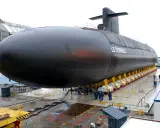 Le sous-marin "Le Terrible" est en cours de construction, sa taille impressionnante est mise en valeur sur des supports jaunes.