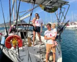 Famille souriante sur un voilier, prête pour une aventure transatlantique à voile.
