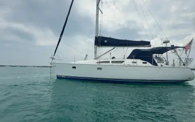 Voilier blanc à l'ancre, voiles bleues repliées. Un avis sur le Sun Odyssey 37, prêt pour l'aventure.