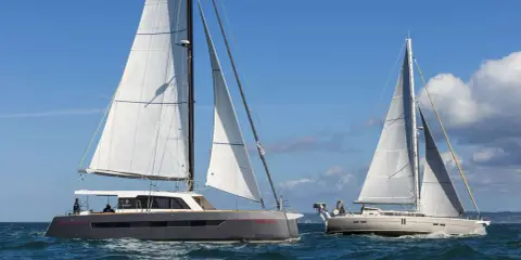 Deux grands voiliers naviguent sur une mer bleue sous un ciel clair.