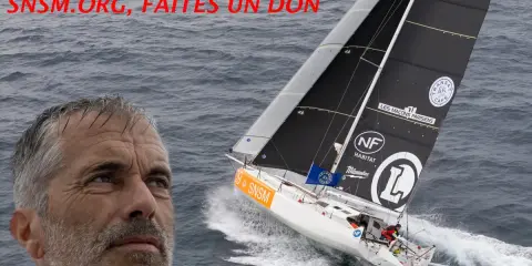 Le visage de Corentin Douguet, skipper, à côté de son voilier blanc et noir naviguant sur une mer agitée. SNSM.ORG, faites un don.