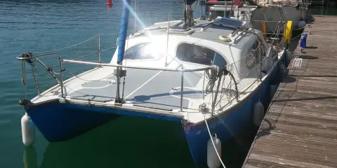 Un catamaran Hirondelle bleu et blanc, amarré à un ponton en bois, prêt pour une nouvelle aventure sur l'eau.